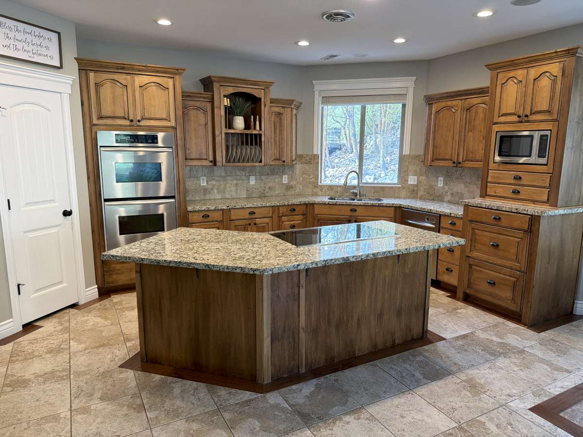 Kitchen featuring light stone countertops, wood finish cabinets, stainless steel appliances, a center island, and tasteful backsplash