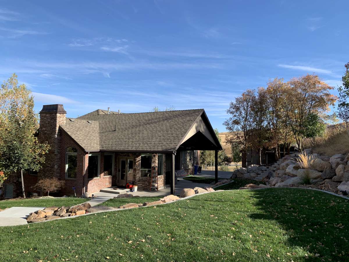 View of front of property with a front yard, a chimney, brick siding, a shingled roof, and covered porch