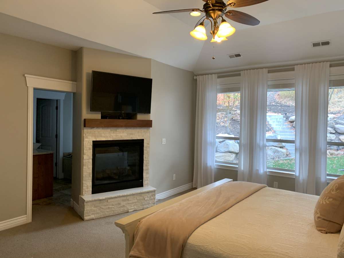 Bedroom featuring carpet floors, a ceiling fan, a fireplace, and vaulted ceiling