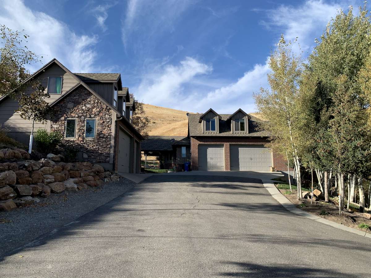View of front of home featuring stone siding, a garage, and asphalt driveway