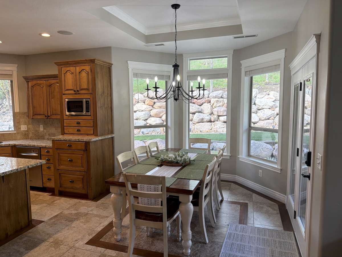 Dining room featuring plenty of natural light, stone tile floors, hanging lights, a tray ceiling, and crown molding