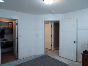 Unfurnished bedroom featuring a walk in closet and baseboards