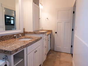 Bathroom featuring two vanities and light tile patterned floors