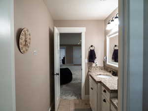 Bathroom featuring vanity, light tile patterned flooring, and a textured ceiling