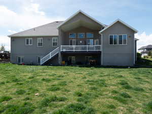 Back of house featuring a lawn and stucco siding