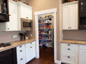 Kitchen featuring stainless steel appliances, white cabinets, dark wood-type flooring, and extractor fan