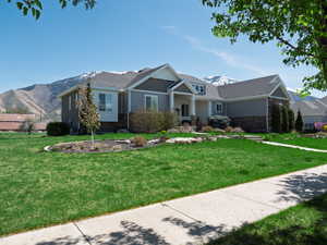 Craftsman house featuring covered porch, a mountain view, a front yard, and stone siding