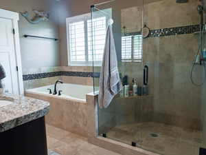Full bath featuring vanity, a garden tub, a shower stall, and light tile patterned floors