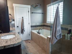 Full bathroom featuring double vanity, a bath, and light tile patterned floors