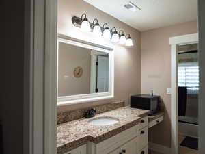 Bathroom with vanity, a textured ceiling, and enclosed tub / shower combo
