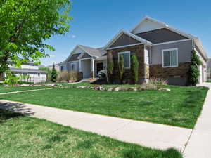 Craftsman inspired home featuring a front lawn and stone siding