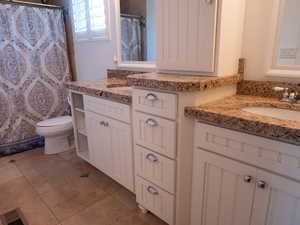 Full bath with two vanities, a shower with curtain, and light tile patterned floors