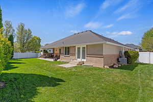 Rear view of property with a fenced backyard, brick siding, a patio, and french doors