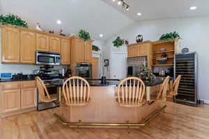 Kitchen with light wood finished floors, beverage cooler, a center island, stainless steel appliances, and a breakfast bar area