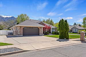 Single story home featuring brick siding, a gate, an attached garage, concrete driveway, and a shingled roof
