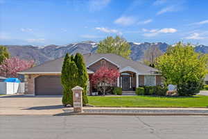 View of front facade featuring a front lawn, an attached garage, brick siding, a mountain view, and driveway
