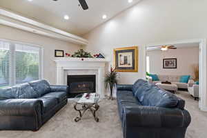 Carpeted living room featuring a ceiling fan, vaulted ceiling, a premium fireplace, and recessed lighting