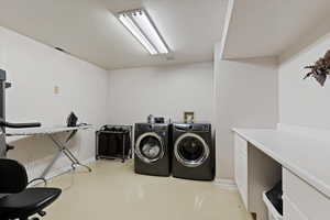 Laundry area with a textured ceiling, washer and dryer, and finished concrete floors