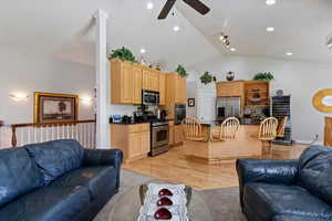 Living room featuring a ceiling fan, light wood-type flooring, lofted ceiling, and beverage cooler