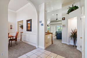 Hallway with light colored carpet, arched walkways, and light tile patterned floors