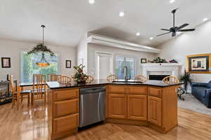 Kitchen with open floor plan, light wood finished floors, a ceiling fan, wood finish cabinets, and vaulted ceiling