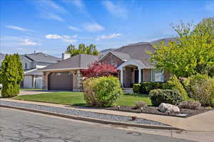 View of front of property featuring a garage, a front yard, driveway, brick siding, and a chimney