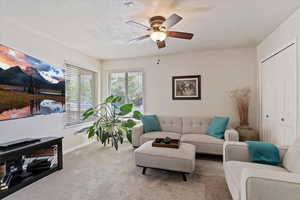 Living area with carpet floors, ceiling fan, and a textured ceiling