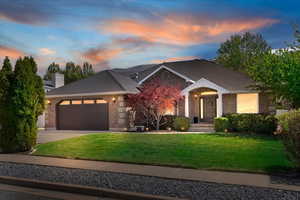 View of front of house featuring a yard, a garage, brick siding, driveway, and a chimney