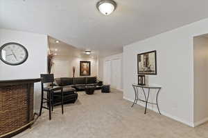 Living area with light colored carpet, a textured ceiling, and recessed lighting