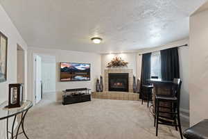 Carpeted living area featuring a textured ceiling and a tiled fireplace