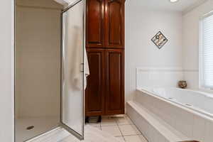 Full bathroom with a shower stall, light tile patterned floors, and a garden tub