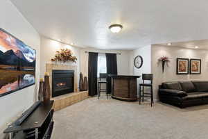 Living room with light colored carpet, a textured ceiling, a fireplace, and recessed lighting