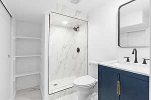 Full bath featuring vanity, a marble finish shower, and light marble finish floors