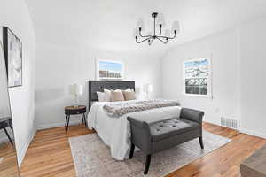 Bedroom featuring lofted ceiling, light wood-type flooring, and hanging lights