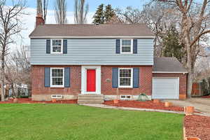 Colonial home featuring a chimney, driveway, a garage, a shingled roof, and entry steps