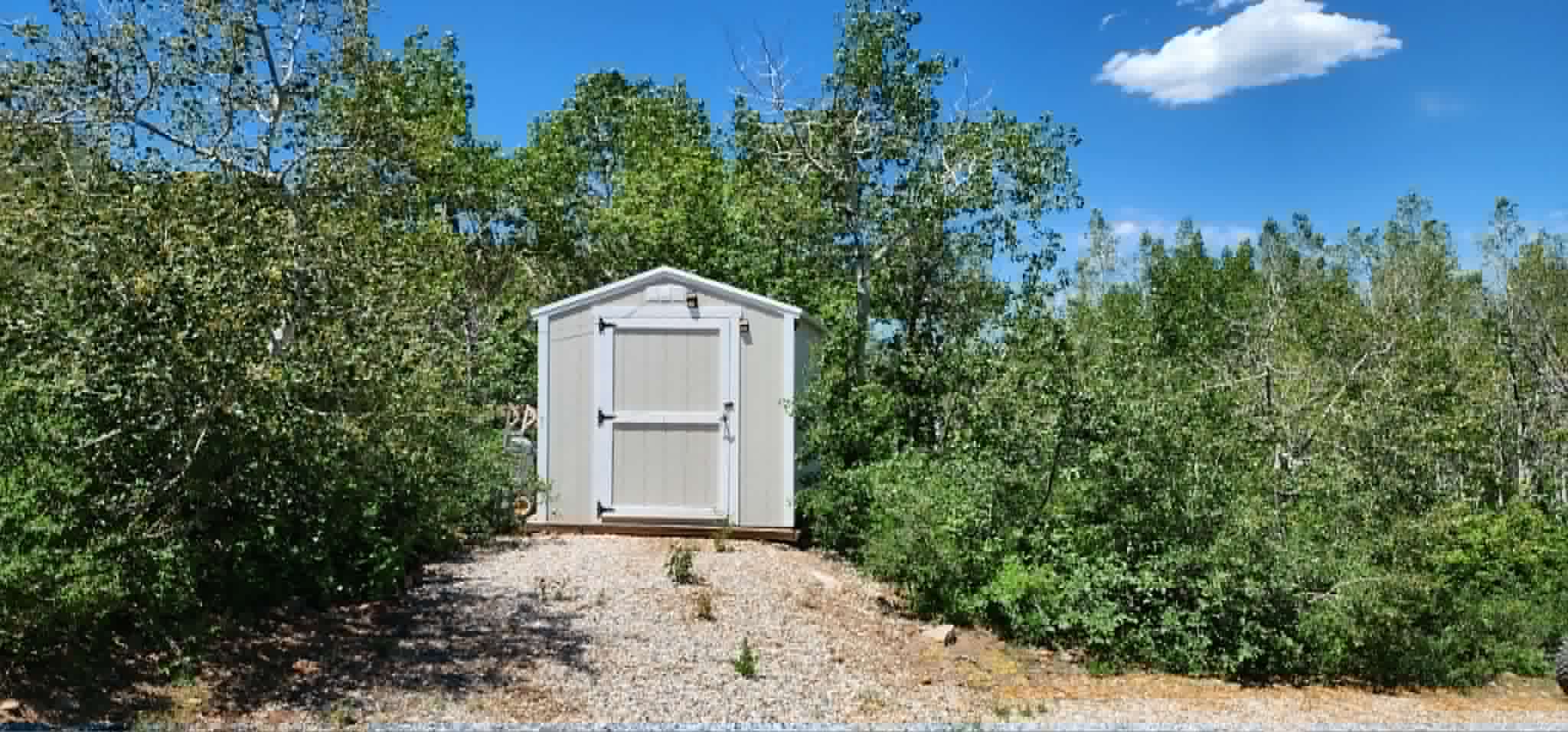 Exterior storage shed featuring a gable roof, double doors, and a wood foundation