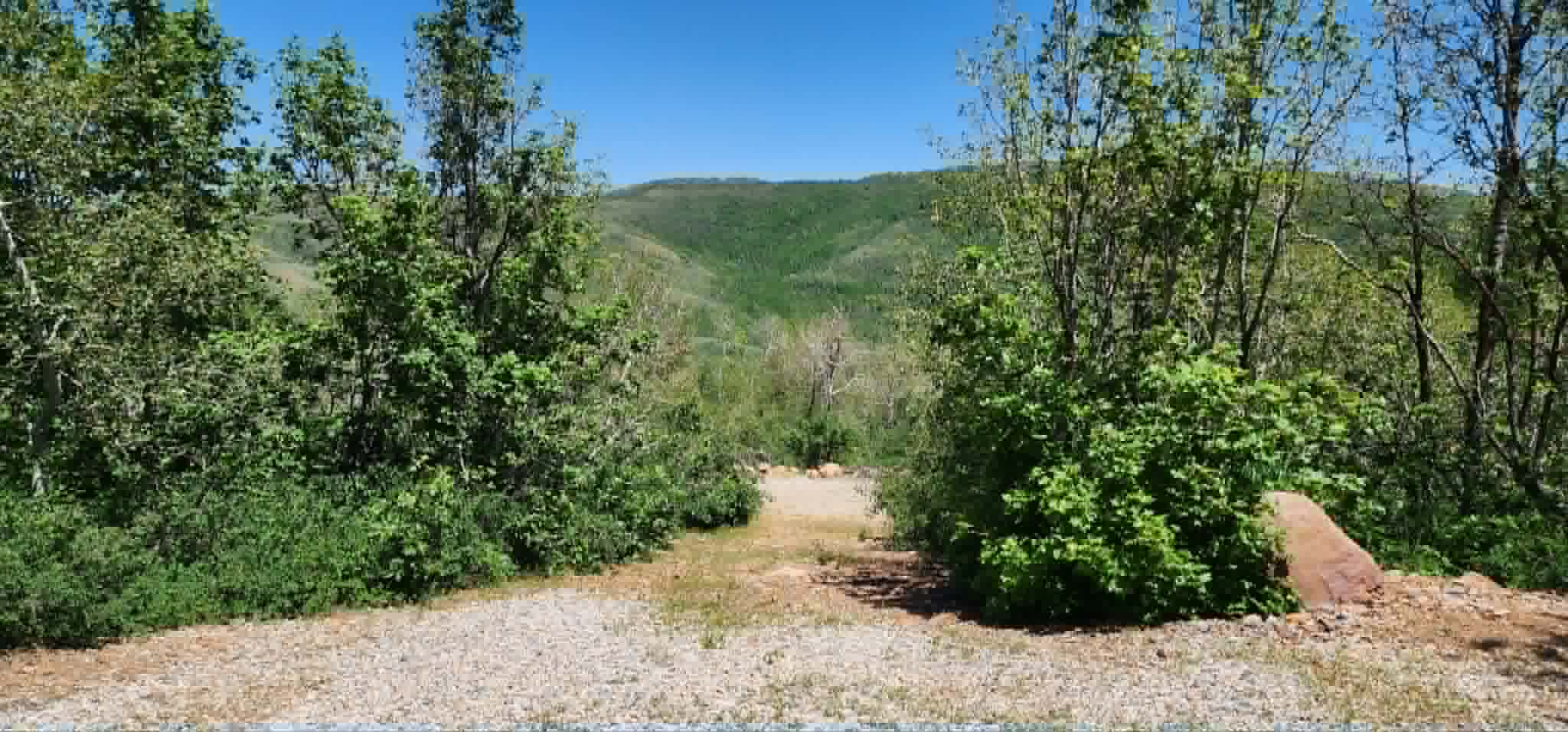 Expansive natural setting featuring a gravel foreground and a backdrop of verdant hills
