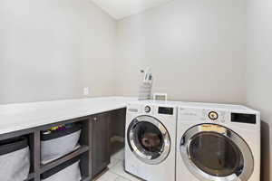 Laundry room with washing machine and clothes dryer and light tile patterned floors