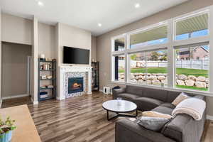 Living area with dark wood-style flooring, a tile fireplace, and recessed lighting