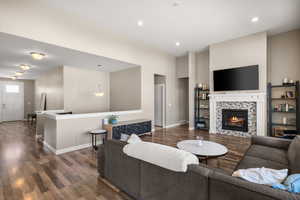Living area with dark wood-type flooring, a tile fireplace, and recessed lighting