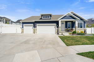 Craftsman house with a gate, stone siding, an attached garage, concrete driveway, and covered porch