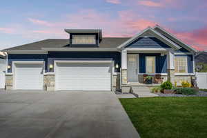 Craftsman inspired home with stone siding, an attached garage, a yard, and concrete driveway