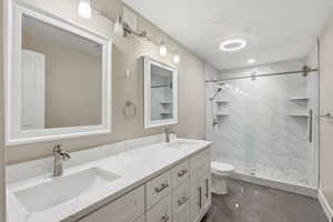 Bathroom featuring double vanity, a shower stall, and dark tile patterned flooring