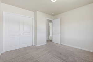 Unfurnished bedroom with light colored carpet and a closet