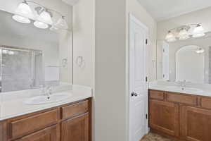 Bathroom featuring two vanities, a stall shower, and suspended lighting
