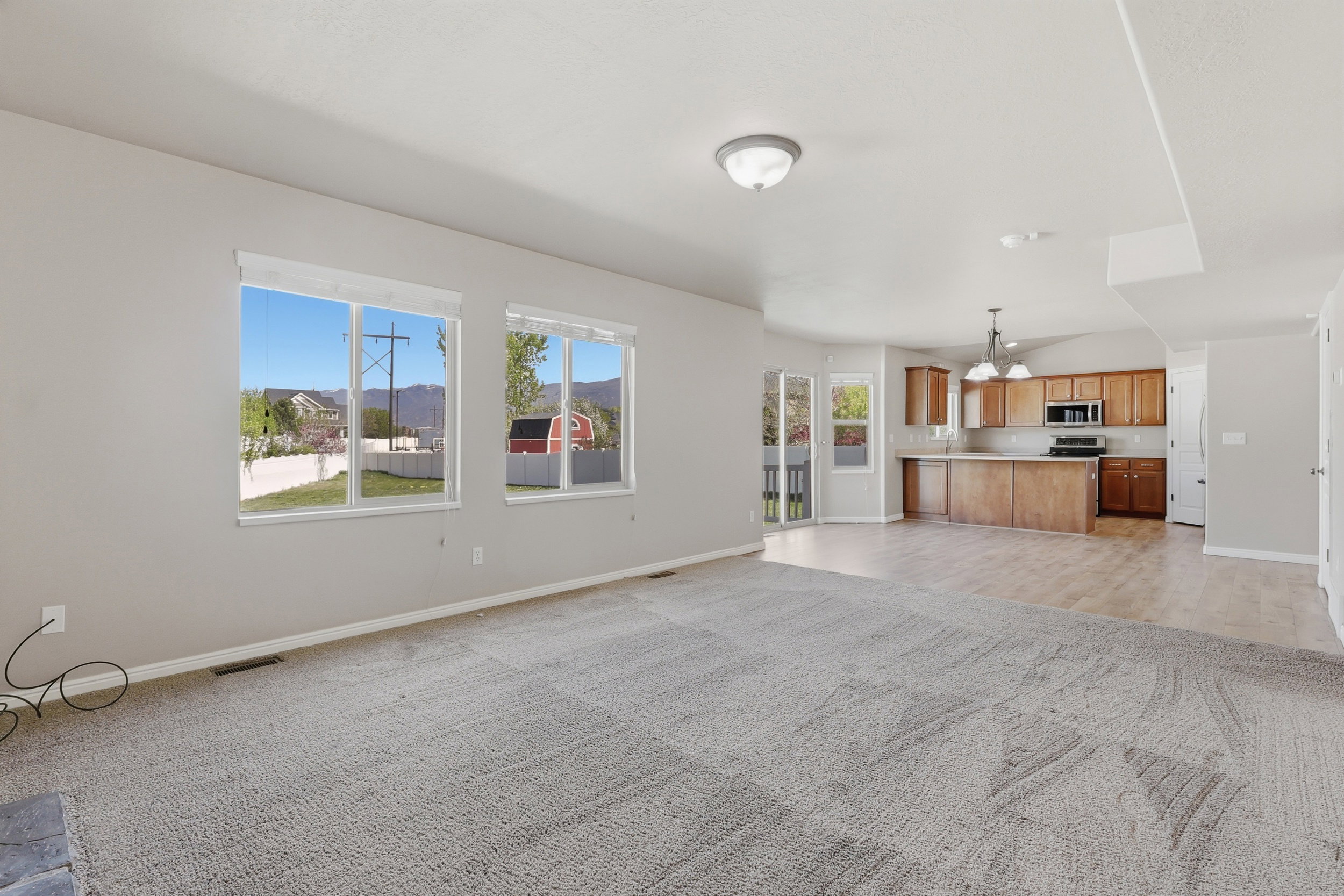 Unfurnished living room featuring light carpet, suspended lighting, and a mountain view
