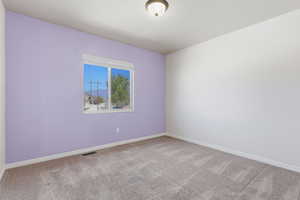 Unfurnished room featuring baseboards and light carpet