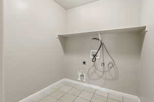 Laundry area with washer hookup, electric dryer hookup, and light tile patterned floors