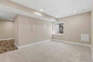 Below grade area with light colored carpet, recessed lighting, and electric panel
