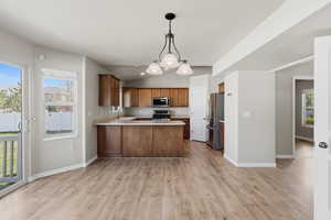Kitchen with vaulted ceiling, a peninsula, light countertops, stainless steel appliances, and light wood finished floors
